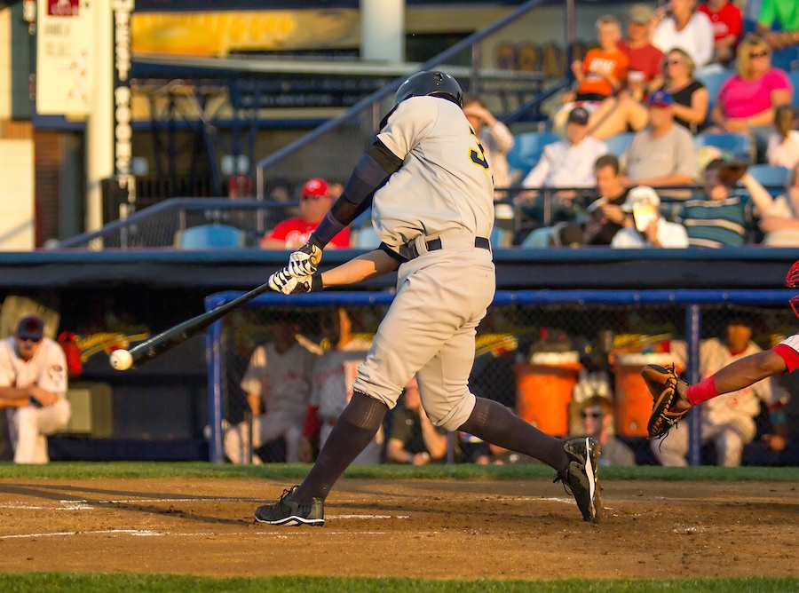 A baseball player is hitting the ball with the bat while there are viewers in the stadium behind him