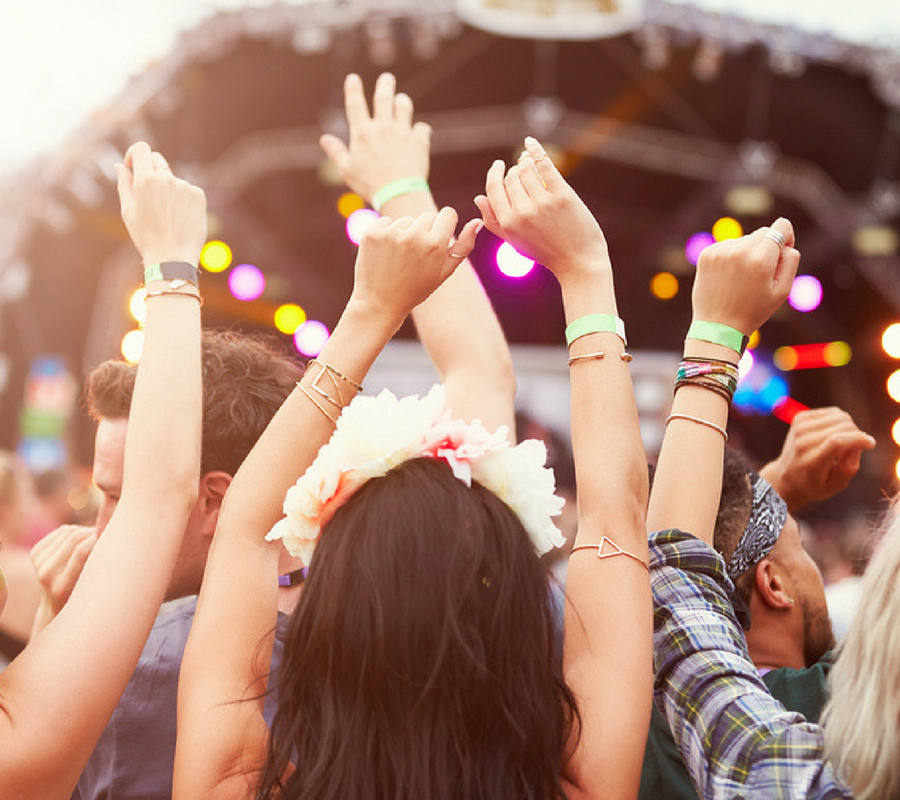 Close up of people throwing their hands in the air at an outdoor concert