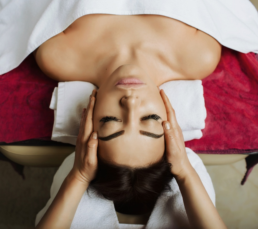 A woman getting a massage at a spa with two hands rubbing her head