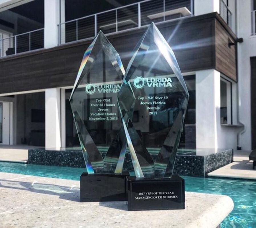 Two crystal awards from Florida VRMA in front of a house with a pool