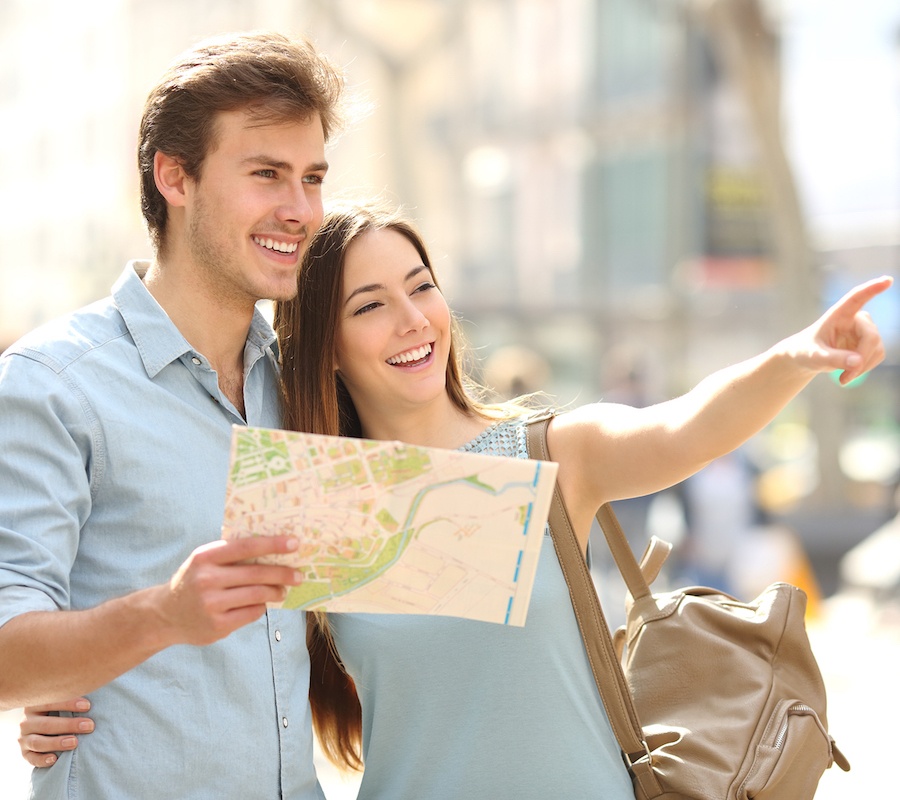 A man and a woman holding up a map and pointing to what they see ahead