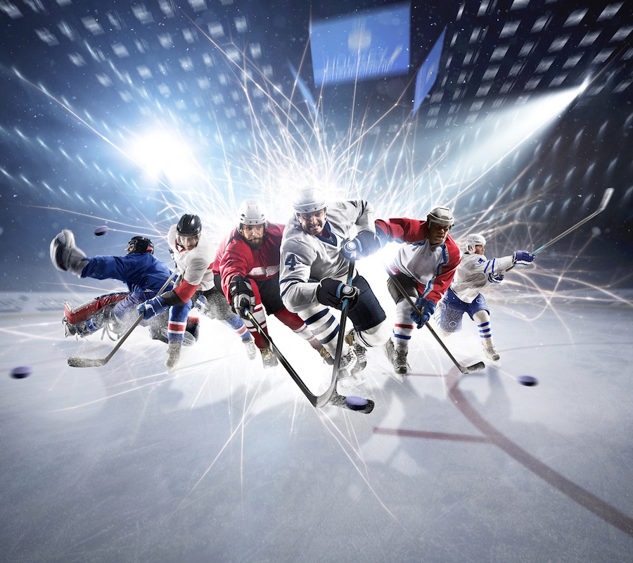 An intense photo of hockey players all charging towards the camera with lights flashing behind them