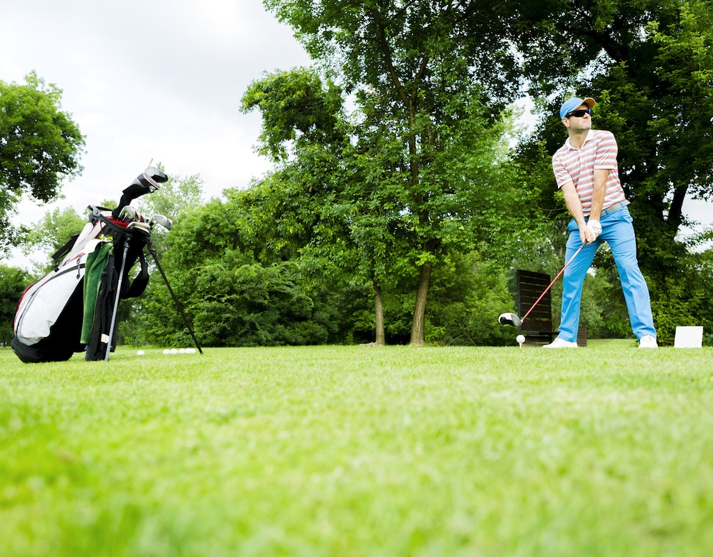 A man playing golf with his golf clubs to the left of him