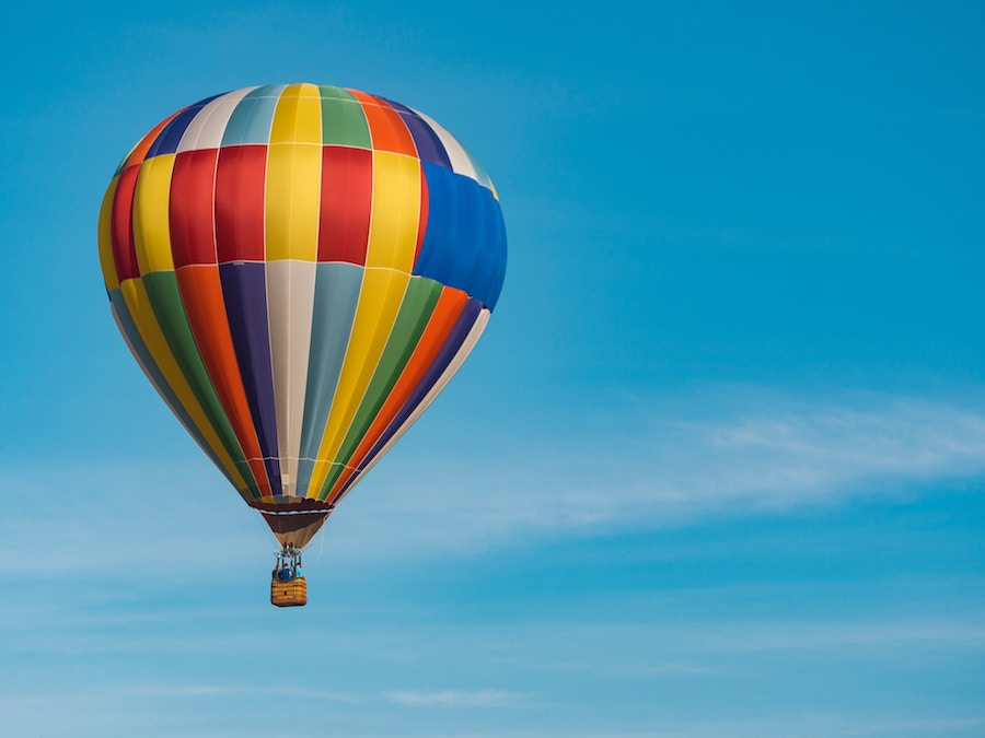 A close up image of a rainbow hot air balloon in the sky