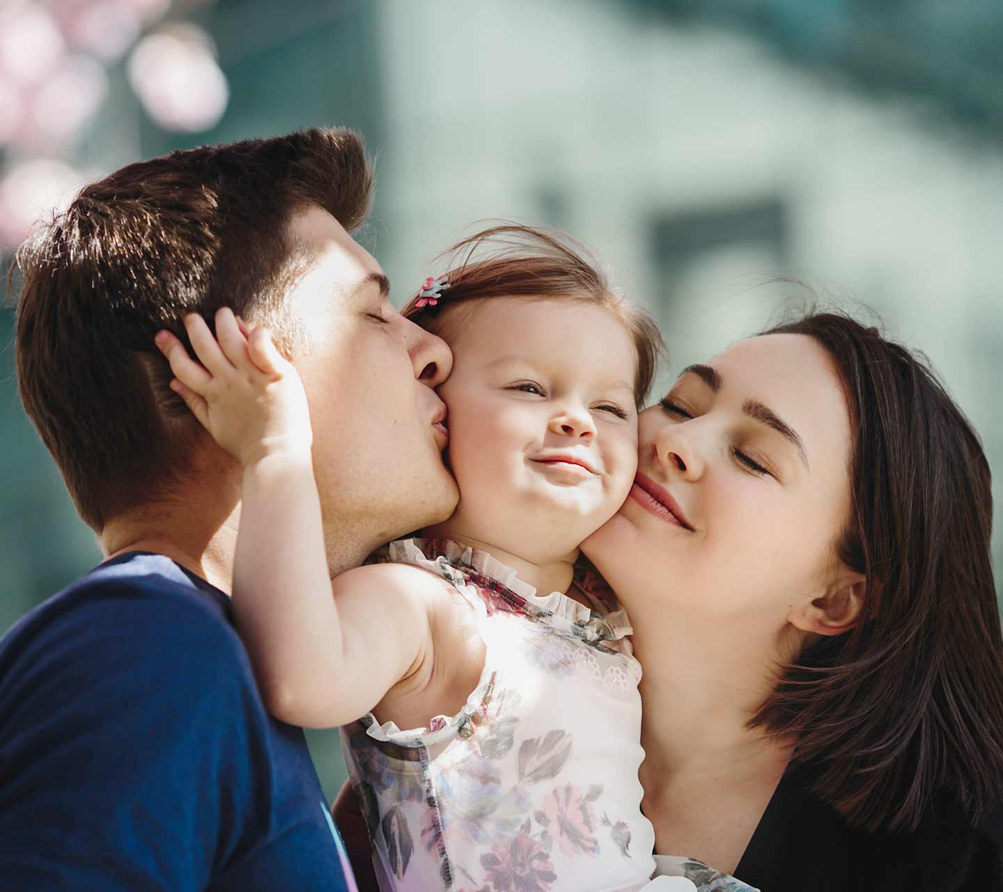 Baby being held up and kissed by mother and father